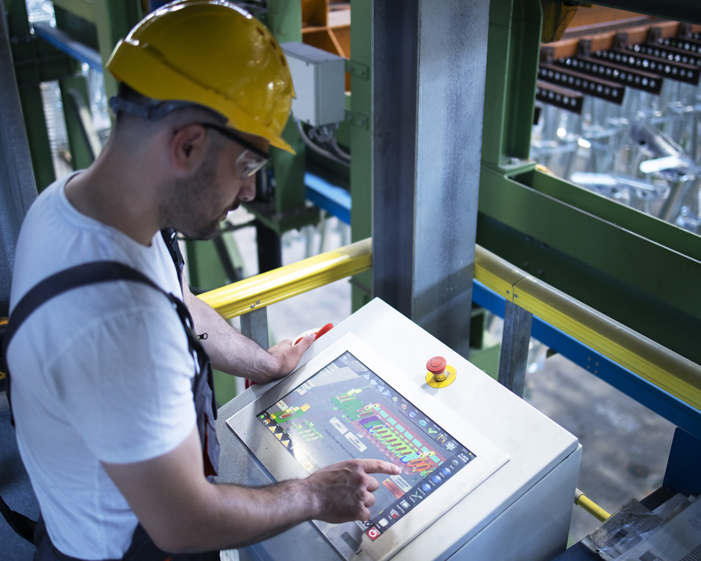 Factory worker monitoring industrial machines and production remotely in control room.